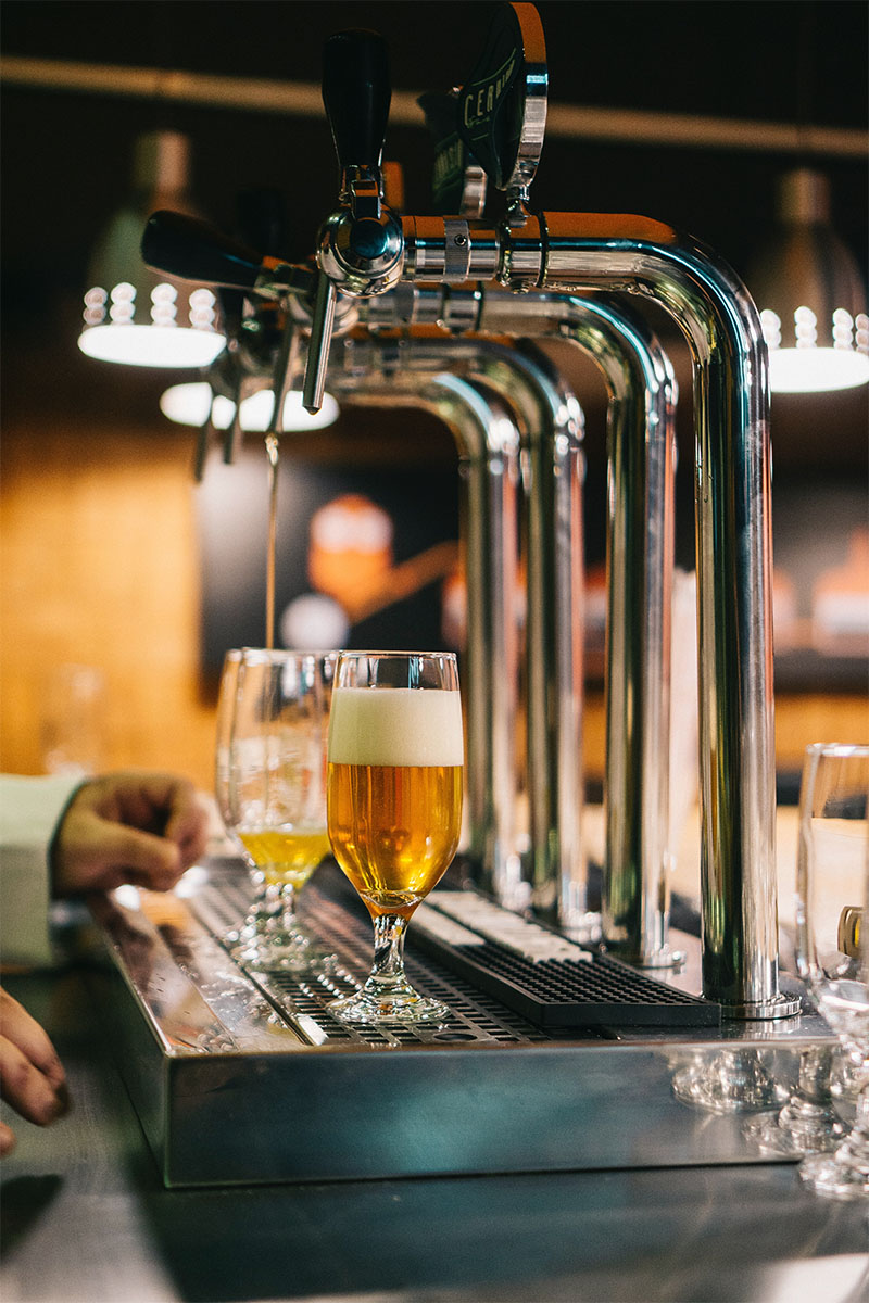 Bartender filling beer glasses at tap.