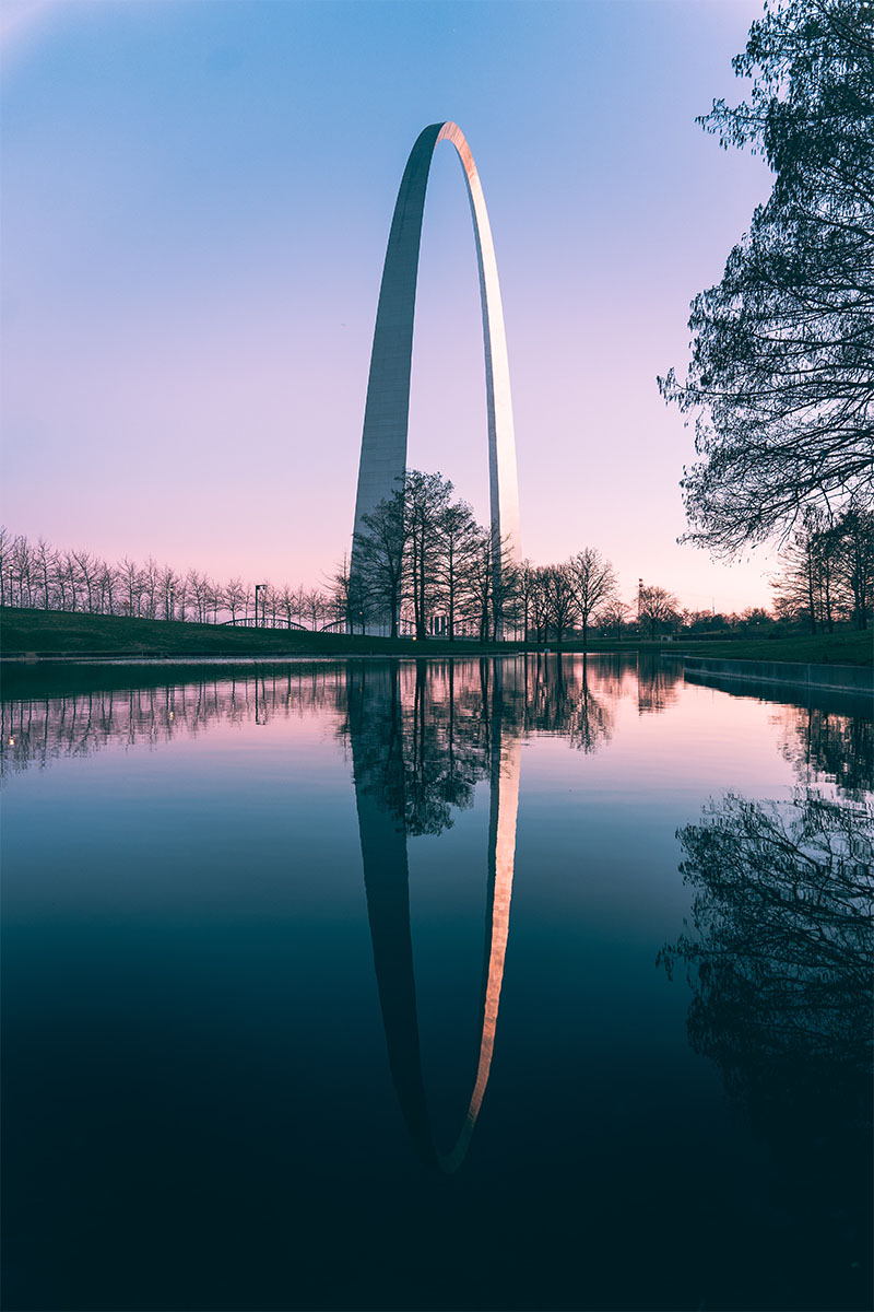 Gateway Arch reflected in pond at dusk.