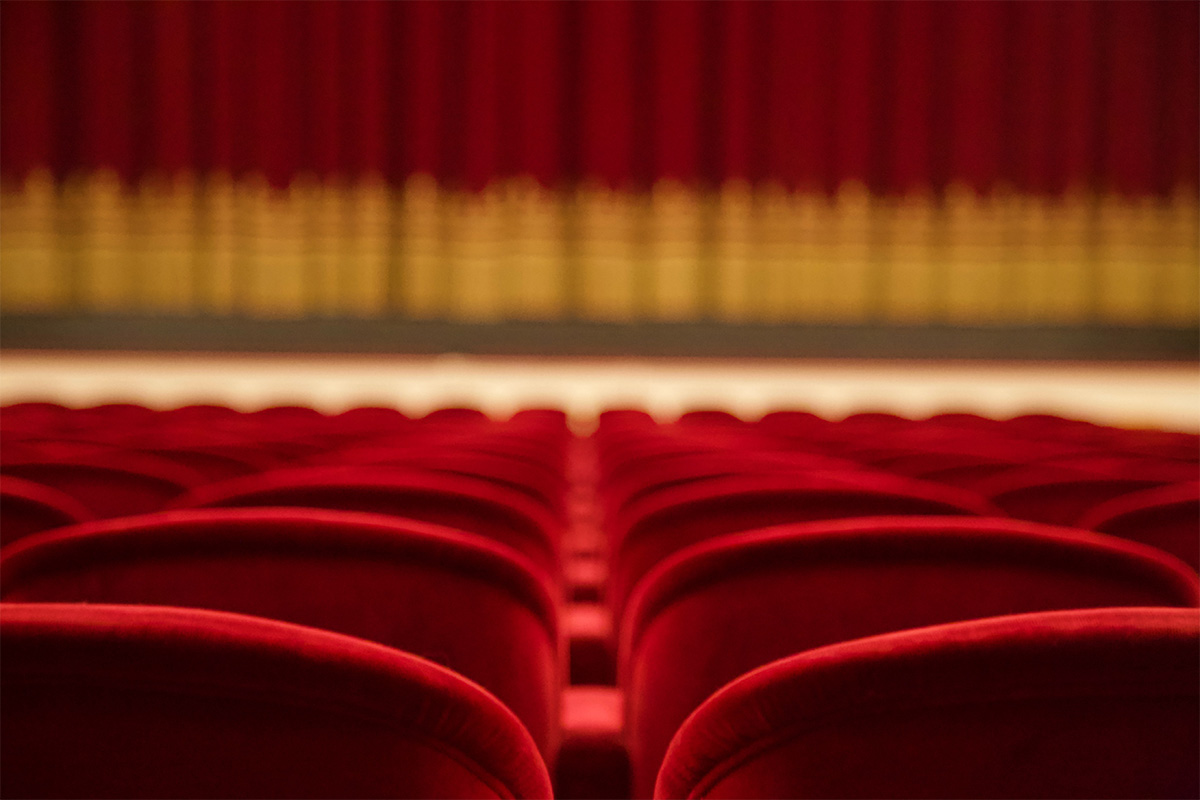 Theater with red curtains and red velvet chairs.